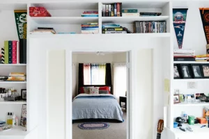 Unique reading nook with bookshelves above a doorway.